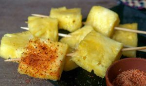 Fresh pineapple chunks on skewers, dusted with chili, salt, and lime.